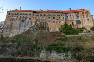 Yüksek taş duvarları ve kırmızı çatıları olan tarihi Avrupa kalesi.