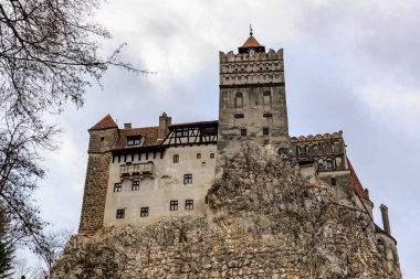 Bulutlu gökyüzünün altındaki kayalık uçurumdaki görkemli ortaçağ kalesi.