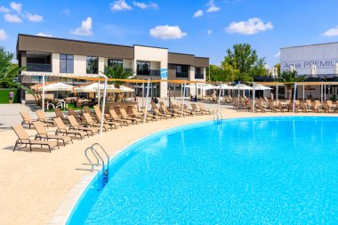 Birçok şezlonga ve şemsiyeye sahip büyük bir havuz birçok sandalye ve şemsiyelerle çevrilidir. Havuz bir sürü penceresi olan bir binada, ona parlak ve davetkar bir atmosfer sağlıyor. 8 Haziran 2024 Balti Moldova