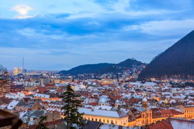 Gökyüzünde dolunay olan bir şehir. Şehir ışıklarla aydınlanıyor ve ay ışıl ışıl parlıyor. 14 Aralık 2024 Brasov Romanya