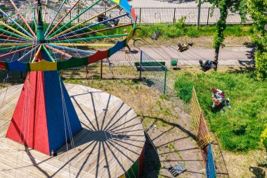 Güneşli bir günde, fazla gelişmiş parkta terk edilmiş renkli bir atlıkarınca. 22 Mayıs 2025 Balti Moldova.