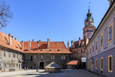 Tarihsel Cesky Krumlov şatosunun bahçesinde canlı bir kule ve açık mavi gökyüzü var. 20 Mart 2025, Cesky Krumlov, Çek.