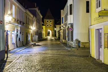Avrupa 'nın tarihi şehrindeki Cobblestone Caddesi' nde gece aydınlık binalar var. 20 Mart 2025, Cesky Krumlov, Çek.