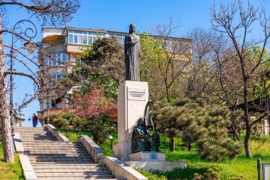 Carmen Sylva 'nın heykeli, taştan heykel üzerinde bronz figürle dolu, yemyeşil bir parkta. 3 Mayıs 2025 Romanya.