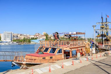 Renkli turist teknesi açık mavi gökyüzünün altında güneşli sahil limanına yanaştı. 3 Mayıs 2025 Romanya.