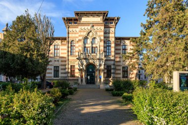 Çiçekli bahçe düzeninde süslü görünüşlü tarihi Venedik gotik binası. 3 Mayıs 2025 Romanya.