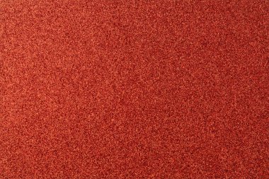 Kırmızı ve turuncu benekli kırmızı bir halı. Halı çok renkli ve çok desenli.