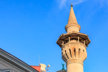 Mimari detaylarla dolu açık mavi gökyüzüne karşı tarihi cami minaresi.
