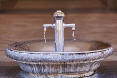 Şehir merkezinde metal ağızları olan zarif bir taş çeşmesi..