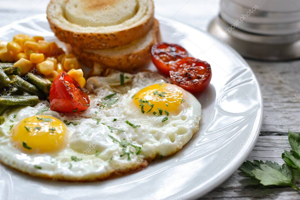 Fried eggs with tomatoes, green beans, corn and toast. English vegetarian breakfast. Coffee and fried eggs close-up. Delicious food