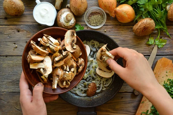 Royal champignons in sour cream sauce. Recipe. Step by step cooking mushrooms with onions. Wood background. Top view. Food in the pan.