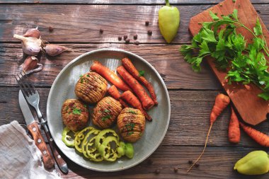 Fırında patates ve havuç. Gri tabak. Ahşap arka plan. Lezzetli ve sağlıklı bir öğle yemeği. Hasselback patatesleri.