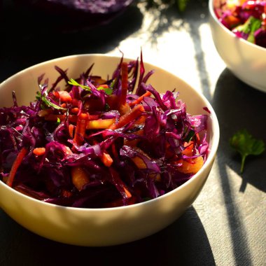 Kırmızı lahana salatası, dolmalık biber ve havuç. Karanlık arka plan. Sağlıklı, parlak yiyecekler.