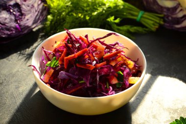 Kırmızı lahana salatası, dolmalık biber ve havuç. Karanlık arka plan. Sağlıklı, parlak yiyecekler.