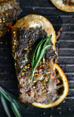 Limonlu ızgara balık, şifalı ot ve biberiye. Izgara tavada kızarmış balık filetosu. Yakın plan..