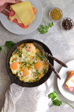 Domatesli sahanda yumurta, soğan ve tavada maydanoz. Peynirli ve sosisli tost. Lezzetli bir kahvaltı. Hafif arkaplan. Üst Manzara. Shakshuka.