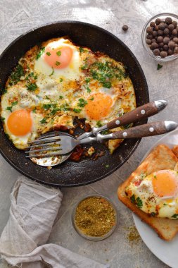 Domatesli sahanda yumurta, soğan ve tavada maydanoz. Peynirli ve sosisli tost. Lezzetli bir kahvaltı. Hafif arkaplan. Üst Manzara. Shakshuka.