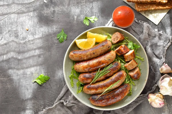 Limonlu ve ketçaplı ızgara sosis. Bitki ve biberiyeli Bavyera sosisi. Gri koyu arka plan. Gri tabak ve keten peçete.