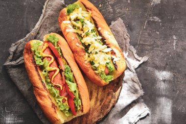 Çeşitli dolgulu sosisliler. Karanlık arka plan. yemek arkaplanı fotokopi alanı. Üst Manzara. Hardallı sosisli, ketçaplı, marullu, peynirli ve domatesli..