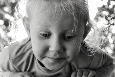 Şirin, sevimli, gülümseyen beyaz beyaz bir çocuğun siyah beyaz portresini kapat. Doğada mutlu bir çocuğun portresi. Mutlu çocukluk kavramı. Bebek kameraya bakıyor. Çocuğun samimi duyguları