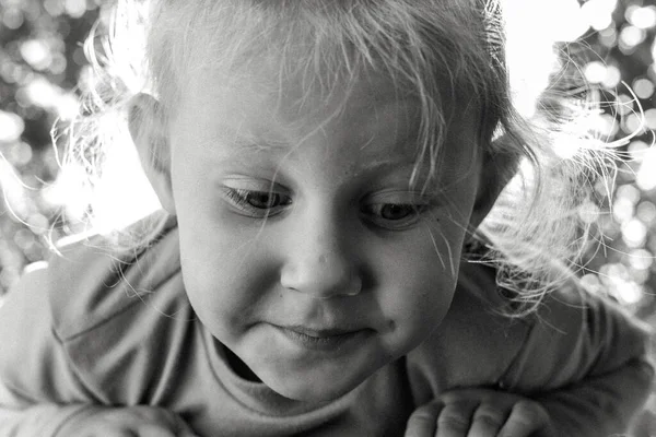 Şirin, sevimli, gülümseyen beyaz beyaz bir çocuğun siyah beyaz portresini kapat. Doğada mutlu bir çocuğun portresi. Mutlu çocukluk kavramı. Bebek kameraya bakıyor. Çocuğun samimi duyguları