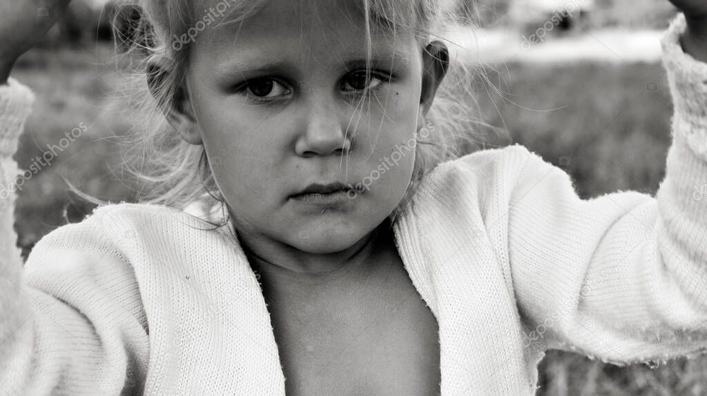 Close up black and white portrait of cute resentful and sad Caucasian child. Children's sincere emotions. Childhood moments. Child in nature.