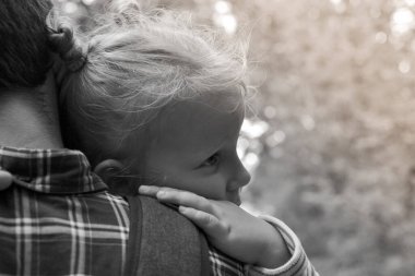Bebek babaya sarılıyor. Babam küçük tatlı bir kızı kollarında tutuyor. Bir çocuğun sonbahar portresi. Mutlu aile ve çocukluk anları.