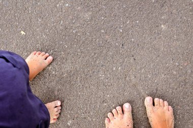 Anne ve çocuğun çıplak ayakları. Anne ve kızı yolda yalınayak duruyorlar..