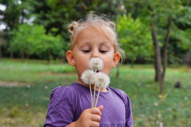 Bahar parkında karahindiba çiçekli güzel bir çocuk. Mutlu çocuk dışarıda eğleniyor..