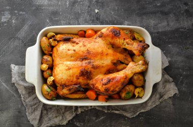 Tam pişmiş tavuk. Metin için boş alan. Gri arka plan. Patatesli tavuk, sarımsak ve havuç. Üst görünüm