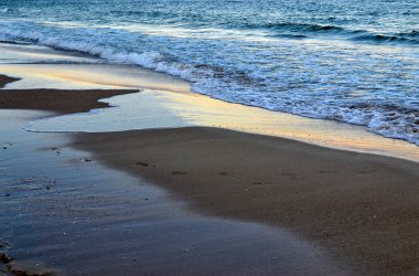 Akşam Denizi kıyısı. Deniz ya da okyanus kıyısında sakin dalgalar.