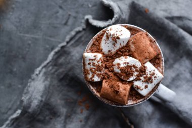 Sıcak çikolata ve lokum. Beyaz bardakta sıcak kakao. Karanlık arka plan. Sonbahar içkisi konsepti. Boşluğu kopyala.