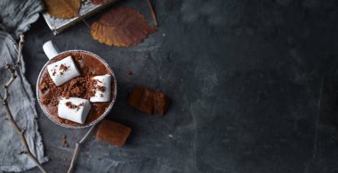 Sıcak çikolata ve lokum. Beyaz bardakta sıcak kakao. Karanlık arka plan. Sonbahar içkisi konsepti. Uzayı kopyala Üst görünüm