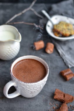 Sıcak çikolata ve lokum. Beyaz bardakta sıcak kakao. Karanlık arka plan. Sonbahar içkisi konsepti. Boşluğu kopyala.
