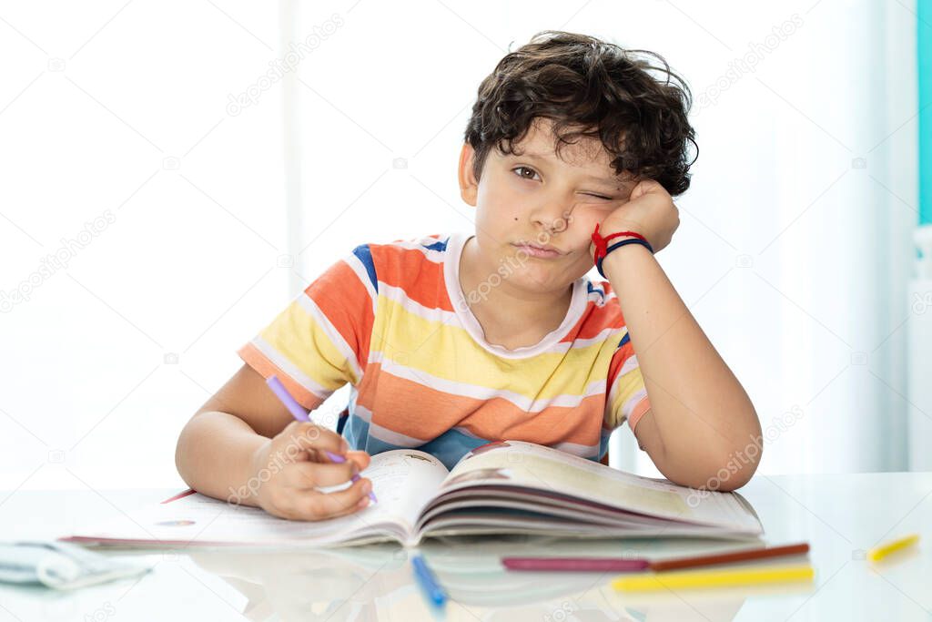Little boy doing homework showing bored expression. Concept of study and education.