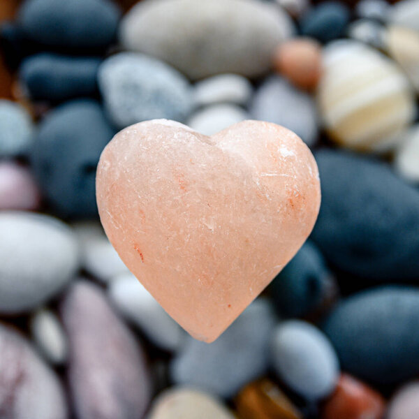 Pink stone heart with rock stones in background. Symbol of love.