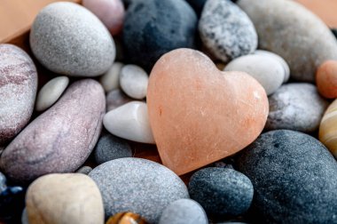 Arka planda kaya taşları olan pembe taş bir kalp. Aşkın sembolü.