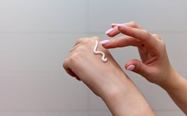 Kadın kozmetik kremiyle elini nemlendiriyor..