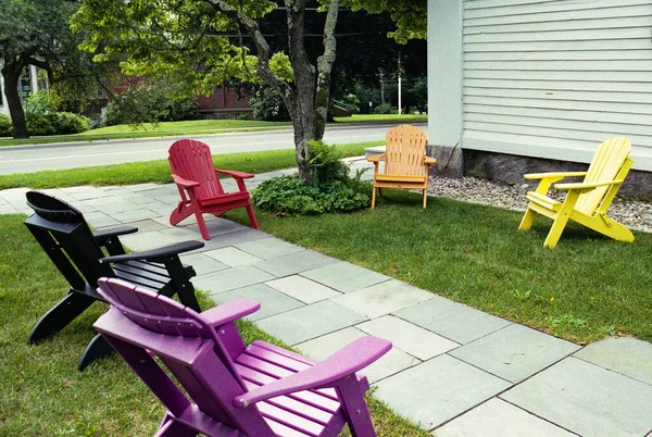 Renkli Adirondack sandalyeleri yaz güneşinde beyaz bir New England kilisesinin önünde sosyal mesafeler için iki metre aralıklarla boş otururlar. Mesafe COVID-19 virüsüne tepki veriyor. Resim analog renk filminde çekildi.