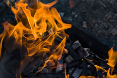 Yeryüzünün ve kömürlerin arka planında yanan parlak ateş.