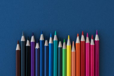 Siyah arkaplandaki çok renkli kalemlerin yatay sırası. Okula dönmek ve okul malzemeleri almak. Eğitici kavram.