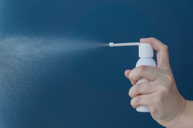 El, mavi arka planda beyaz ilaç şişesini tutuyor. Akciğer hastalıklarının tedavisi, bronşlar ve öksürük. Uzayı metin için kopyala. Sağlık hizmetleri kavramı