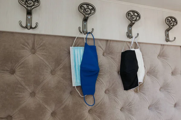 four protective masks of different type hang on home hangers. Obligatory wearing masks due to coronavirus restrictions. Healthcare concept. Protection measures from virus.