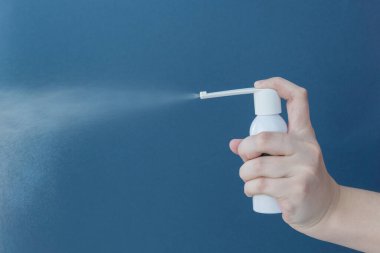  El, mavi arka planda beyaz ilaç şişesini tutuyor. Akciğer hastalıklarının tedavisi, bronşlar ve öksürük. Uzayı metin için kopyala. Sağlık hizmetleri kavramı