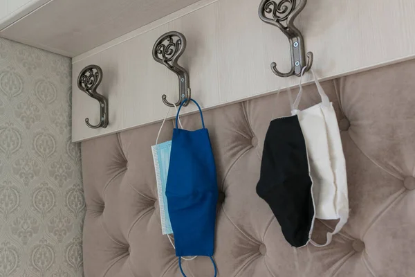 four protective masks of different type hang on home hangers. Mandatory wearing masks outside  due to coronavirus restrictions. Healthcare concept. Protection measures from virus.