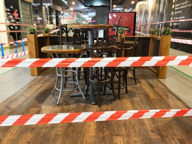 RUSSIA, ROSTOV-ON-DON - 18 Haziran 2020: Alışveriş merkezindeki kafe sandalyeleri ve masalar insanların oturmasını engellemek için şeritli bant ile kaplıdır. Salgından korunma tedbirleri. 