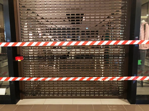 由于封锁的限制 带条纹的边界带覆盖了商场内棕色关闭铁门的商店 防止座无虚席的保护措施 商店破产 — 图库照片