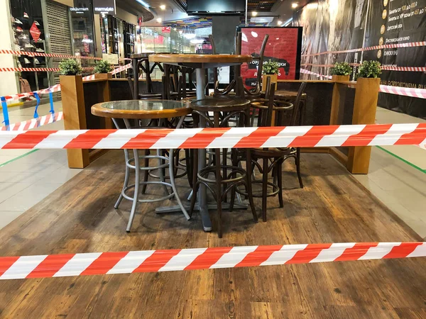 RUSSIA, ROSTOV-ON-DON - 18 Haziran 2020: Alışveriş merkezindeki kafe sandalyeleri ve masalar insanların oturmasını engellemek için şeritli bant ile kaplıdır. Salgından korunma tedbirleri. 