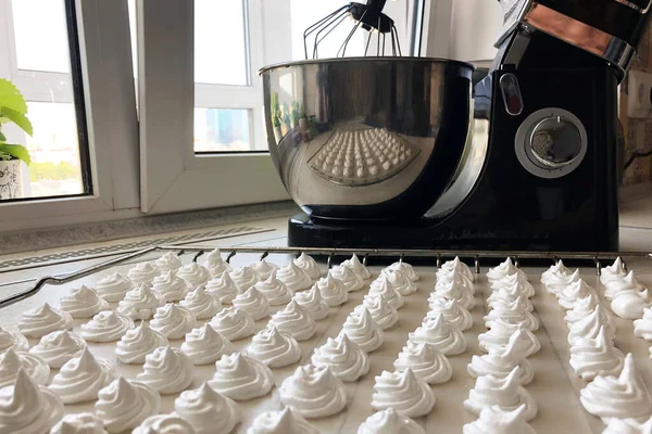 Beyaz ev yapımı marşmelovlar mutfakta sırayla kurutuluyor. Arka planda gezegensel bir şekerleme karıştırıcısı var. Ev konseptinde aşçılık.