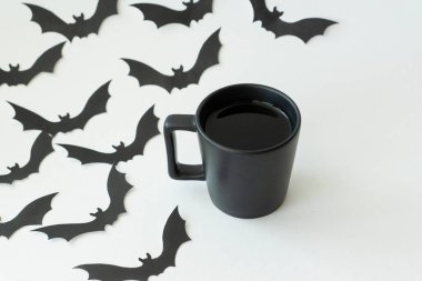 Siyah kağıt cadılar bayramı yarasaları siluetleri ve arka planda bir fincan sıcak çay. Uzayı metin için kopyala. Tatil konsepti için yaratıcı dekorasyonlar.